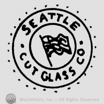 "Seattle Cut Glass Co." written with uppercase letters around a circle with the American banner in the center