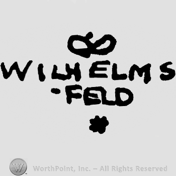 Stylized crown over Wilhelms Feld written with uppercase letters, asterisk below