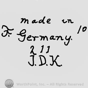 Made in Germany written with lowercase letterss over number 211, precedeed by uppercase handwritten F and followed by number 10, uppercase J.D.K. Written below