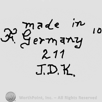 Made in Germany written with lowercase letters over number 211 and uppercase J.D.K., precedeed by uppercase handwritten F and followed by number 10