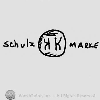 Schulz Marke written on the sides of a circle with uppercase mirrored K inside