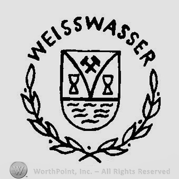 A shield with twi crossed hammers, two chalices and water surroundede by branches with leaves and the word Weisswasser