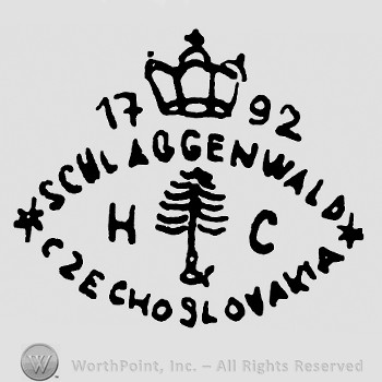 A tree and  letters H C in the middle;a crown with cross and number 1792 on top;words Schlaggenwald and Czechoslovakia written in an oval shape.