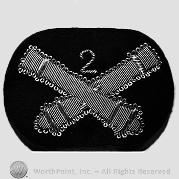 Insignia consisted of two crossed cannons; number 2 above the intersection.