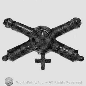 Insignia consisted of crossed cannons and a bullet at the intersection; cross below.