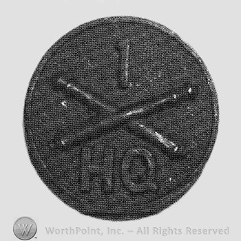 Insignia consisted of crossed cannons and number 1 above, letters HQ below; all on a disc.