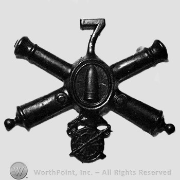 Insignia consisted of crossed cannons with a bullet at the intersection; number 7 above and wheel below.