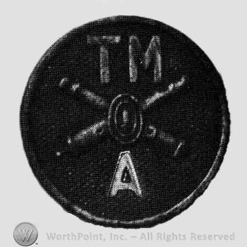 Insignia consisted of crossed cannons and a bullet at the intersection; letters TM above and A below; all on a disc.