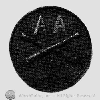 Insignia consisted of crossed cannons and letters AA above and A below; all on a disc.