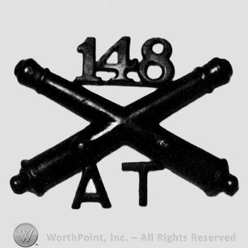 Insignia consisted of crossed cannons and number 148 aboveand letters AT below.