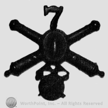 Insignia consisted of crossed cannons with bullet at the intersection and number 7 above; wheel below.