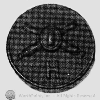 Insignia consisted of crossed cannons with a bullet at the intersection and letter H below; all on a plate.