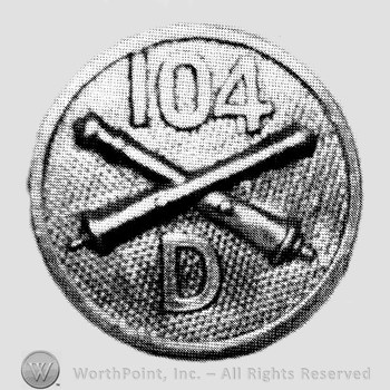 Insignia consisted of crossed cannon, number 104 above and letter D below; all on a plate.