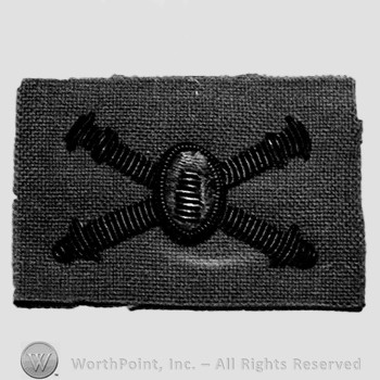 Insignia consisted of crossed cannon with a bullet at the intersection.