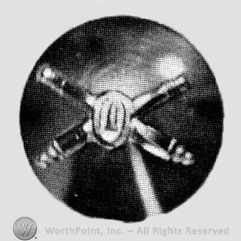Insignia consisted of crossed cannon with a bullet at the intersection; all on a plate.