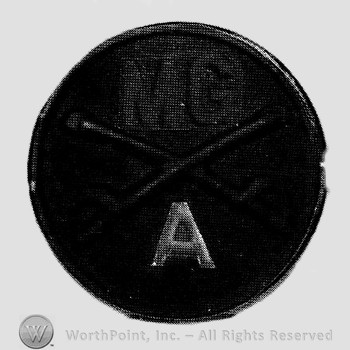 Disc with crossed sabres and letters MG above and letter A below.