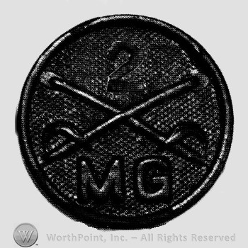 Disc with crossed sabres and number  2 above and letters MG below.