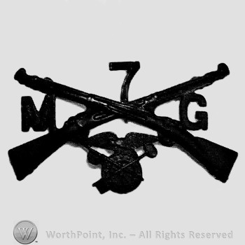 Insignia consisted of crossed rifles, number 7 above the intersection, wheel with wings below and letters M and G on the right and on the left.