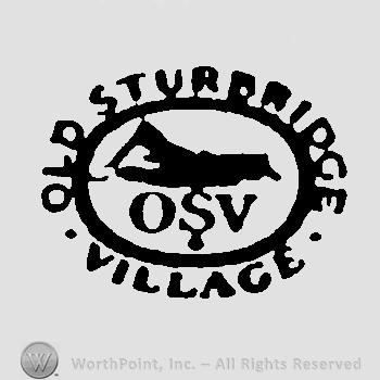 An oval enclosing the sight of a mountain and the initials O, S, V written bellow, the words Old Sturbridge Village written outside the oval in uppercase letters. 
