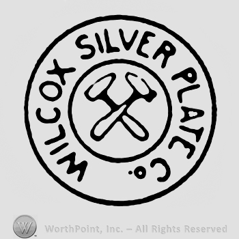 A double circle enclosing two crossed hammers and the text Wilcox Silver Plate Co. written in uppercase letters. 